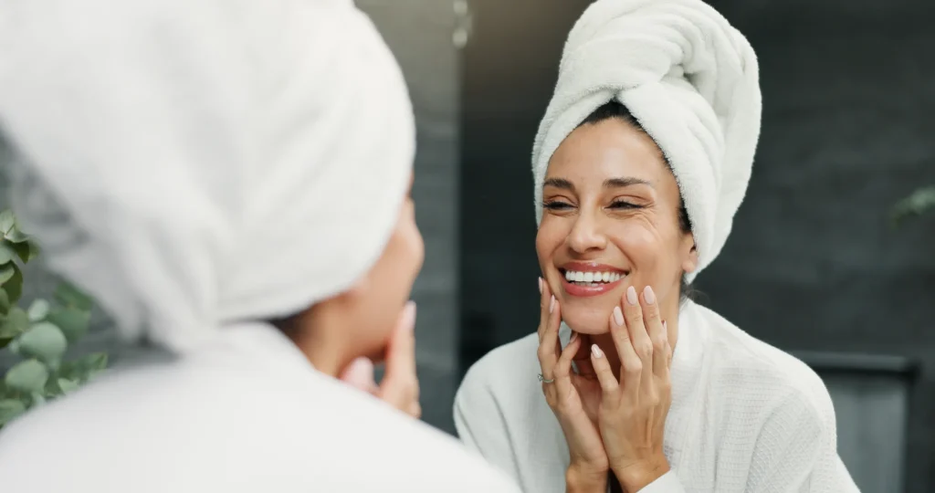 Woman looking in mirror smiling after skin treatment