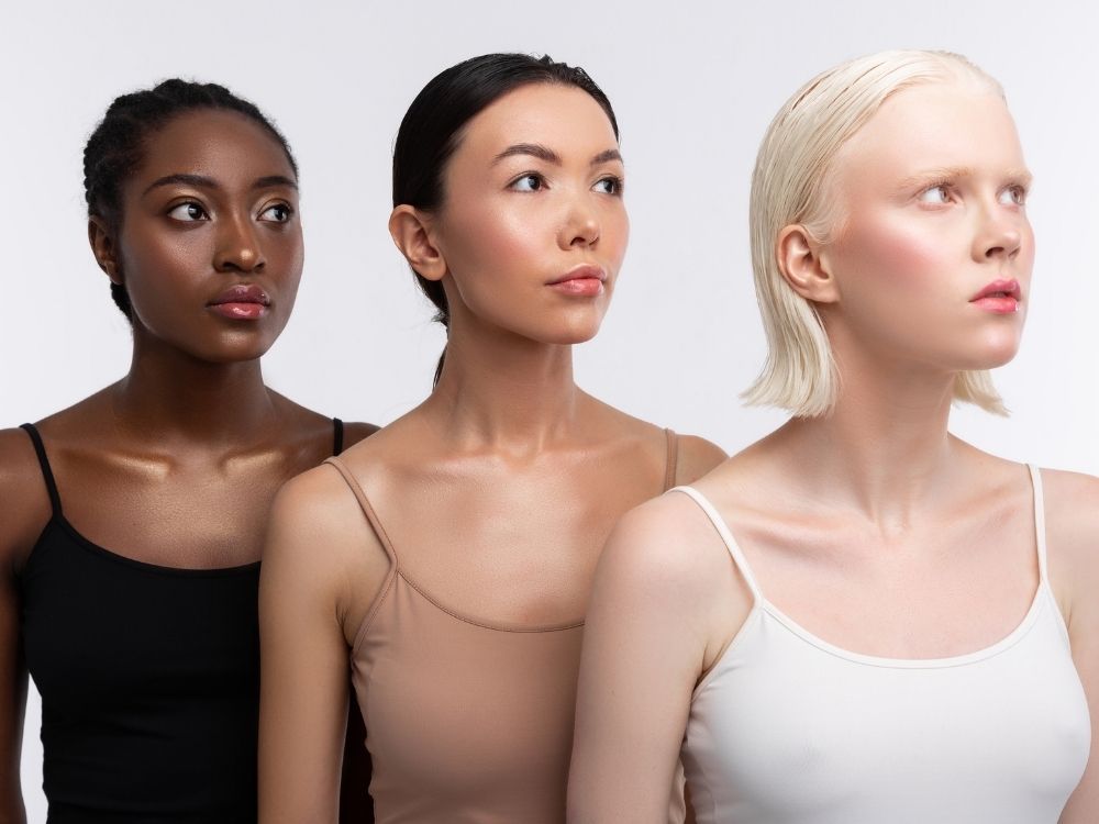three women with different skin tones standing